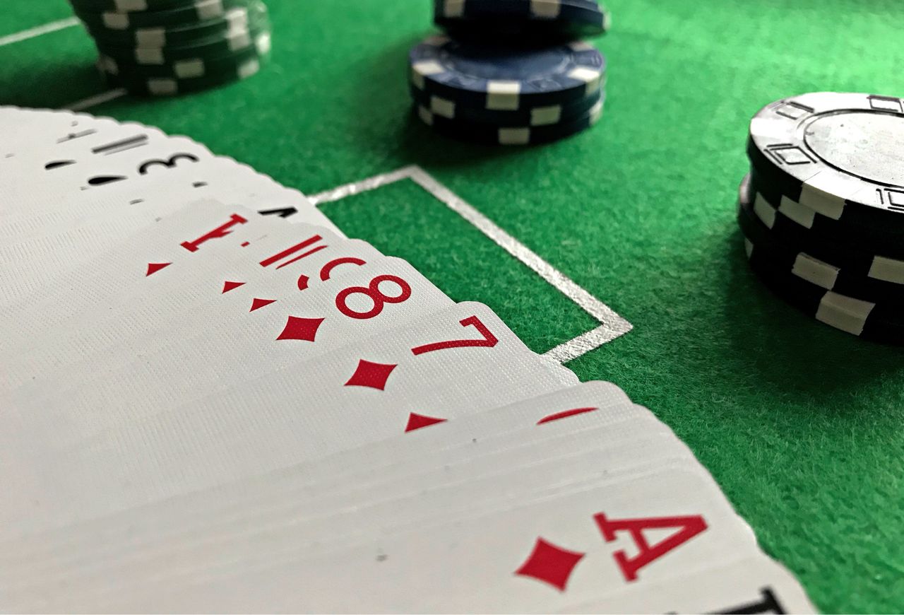 راهنمای جامع شرطبندی ورزشی برای مبتدیان؛ از انتخاب بازار تا مدیریت سرمایه Close-up view of poker cards and chips on a green felt table, perfect for casino-themed content.